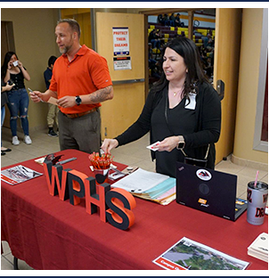 Two West Point High School representatives handing out information at a parent night session
